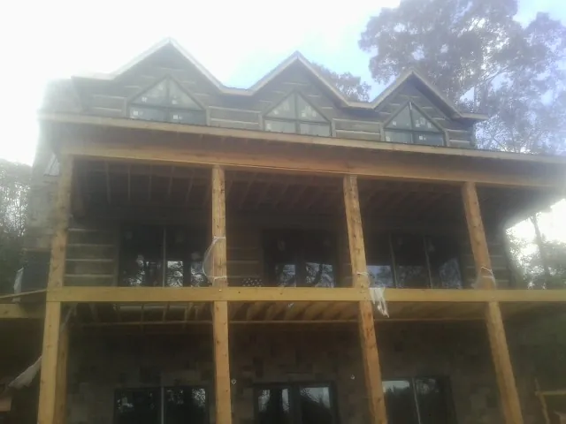 Dormers and porch framing on a large log home under construction — Roof Coating work by our crew in Kent