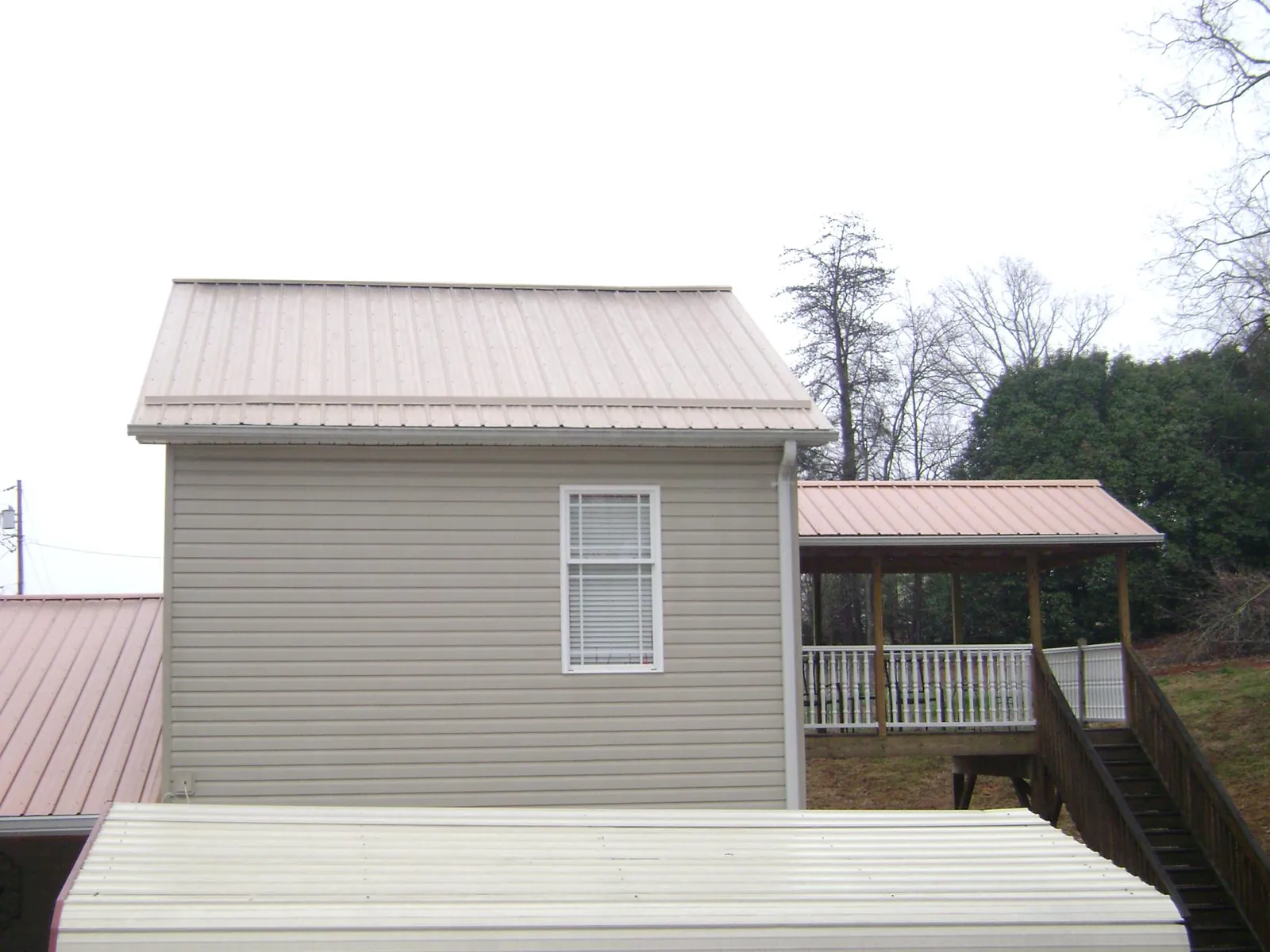 Tan metal roofs on a two story addition and attached porch, from a Roof Replacement job in Kent